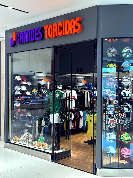 Fachada da loja Grandes Torcidas, com letreiro iluminado e vitrine